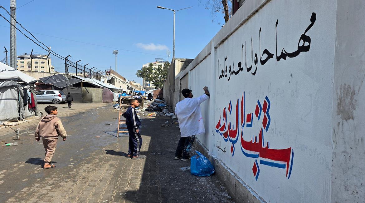 فنانون يرسمون جداريات وكتابات خطية على جدران مدرسة حُوّلت إلى مأوى للنازحين في مدينة غزة