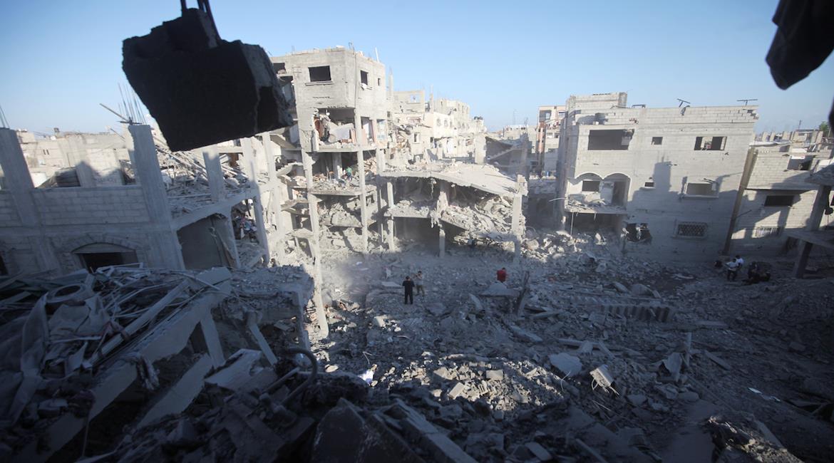  مواطنون يتفقدون آثار الدمار الذي خلفته غارة جوية إسرائيلية استهدفت مبنى في مخيم المغازي وسط قطاع غزة