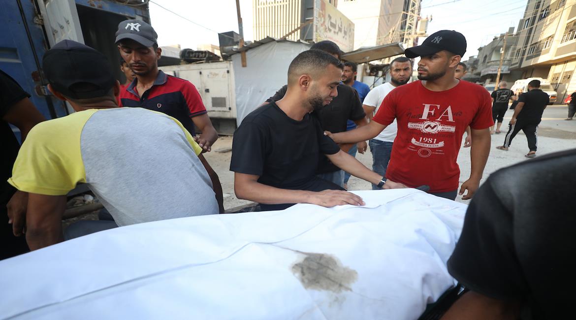 مواطنون ينقلون جثمان شهيد ومصاب في غارة إسرائيلية، إلى مستشفى العودة في مخيم النصيرات وسط قطاع غزة