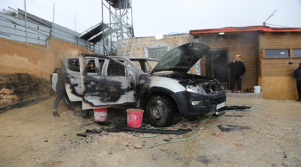 مواطنون يتفقدون مركبةً أحرقها مستعمرون في بلدة حوارة، جنوب نابلس.