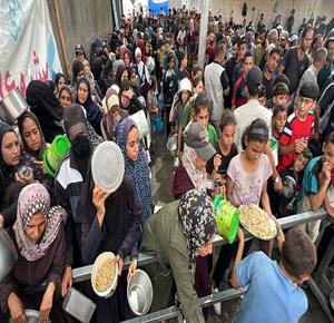 غزة - مواطنون يتجمعون للحصول على طعام مجاني من تكية خيرية في مخيم النصيرات وسط قطاع غزة