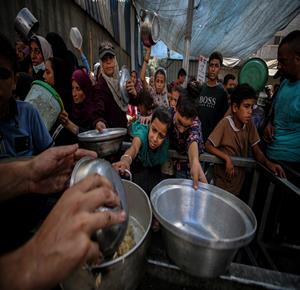 غزة - نازحون يتجمعون للحصول على الطعام المجاني من إحدى التكيات الخيرية في مخيم النصيرات وسط قطاع غزة